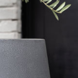 Pax Fiberstone Grau planter by Pottery Pots, featuring a textured gray finish and modern design in a natural setting.